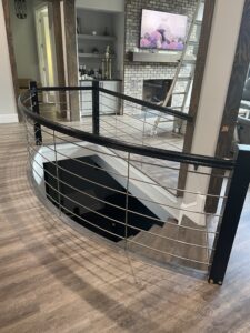 Black steel cable railing around stairwell opening in custom home